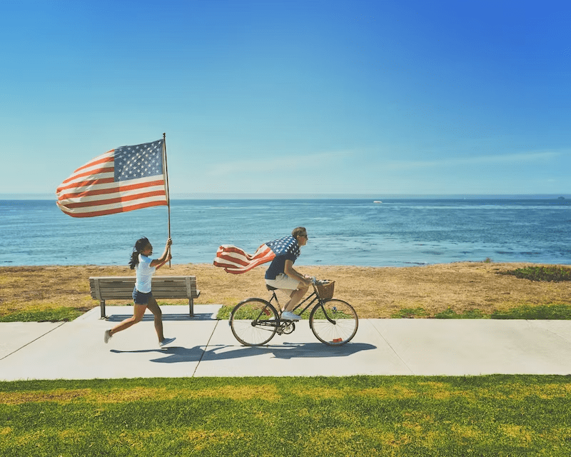 two-people-bike-ride-running-american-flag-ocean