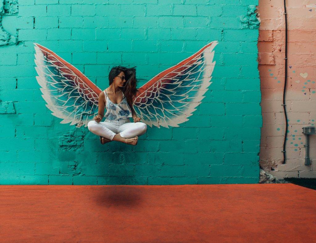 woman-standing-blue-wall-wings-art