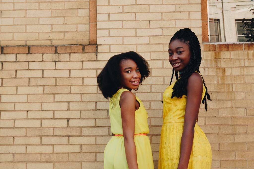 two-african-american-girls-yellow-dresses-brick-wall-background