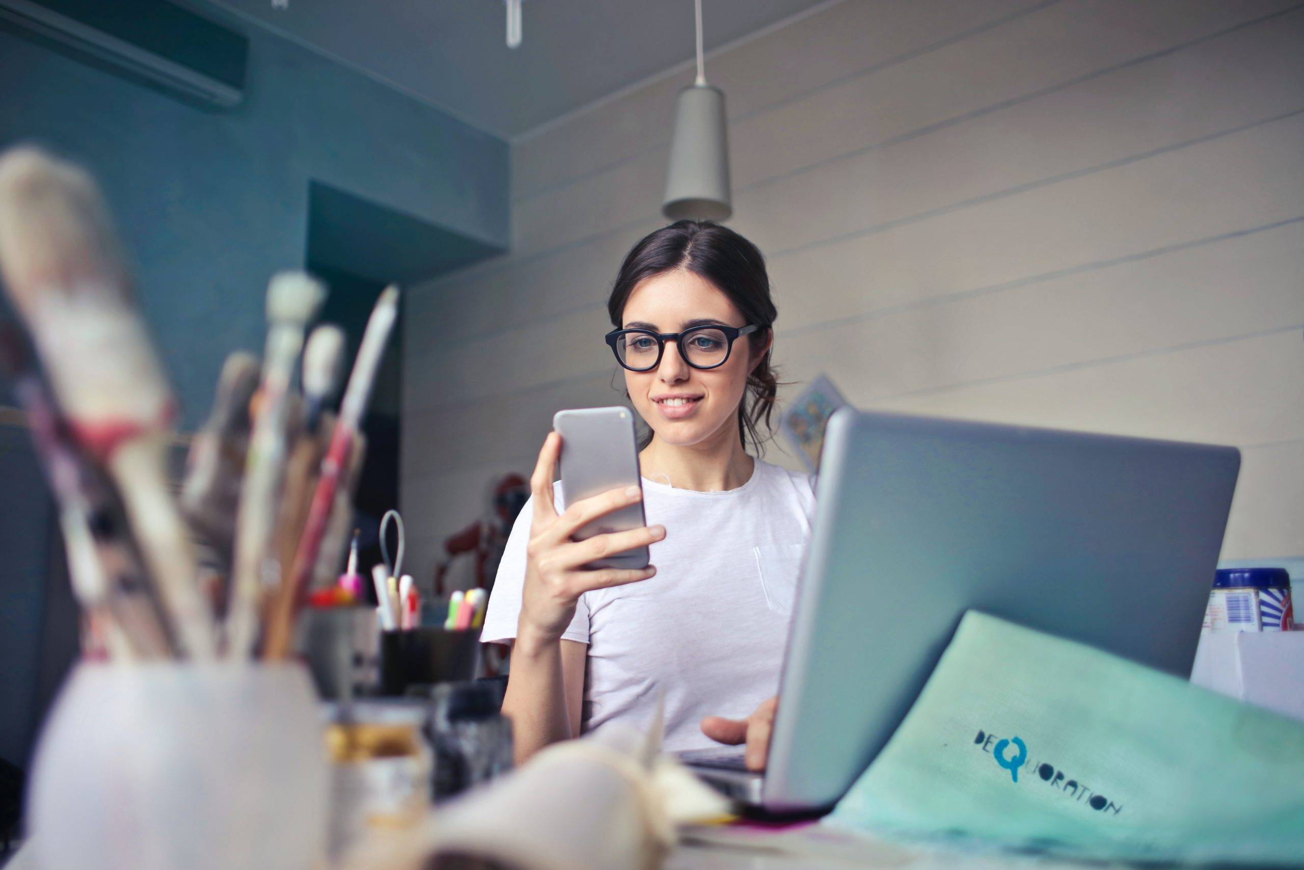 brunette-girl-white-top-wearing-glasses-looking-at-iphone