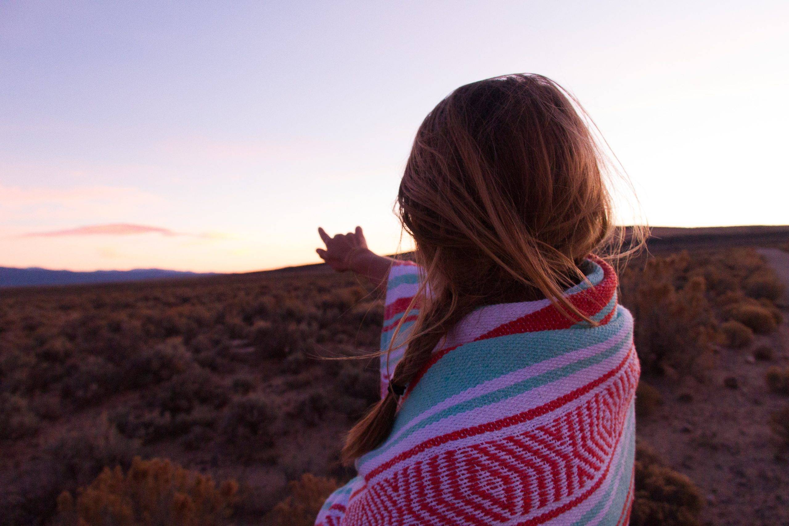 girl-facing-sky-wrapped-in-pink-blanket-taos-new-mexico